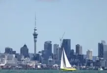 Парусная яхта на фоне небоскрёбов Окленда и башни Sky Tower